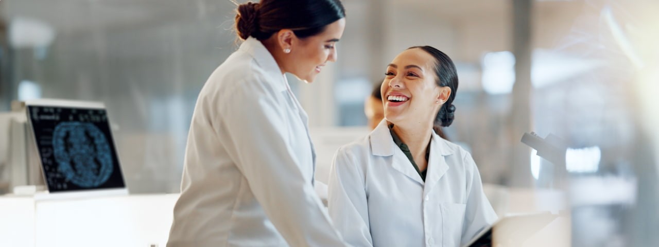 Medical professionals standing by a microscope.